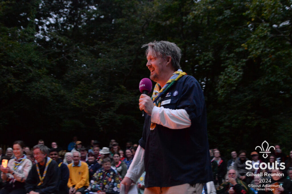 A Scout Leader addresses a camp fire circle